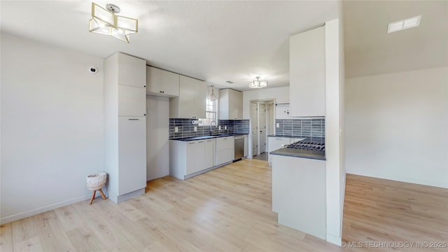 kitchen featuring backsplash, a sink, stainless steel appliances, dark countertops, and white cabinets