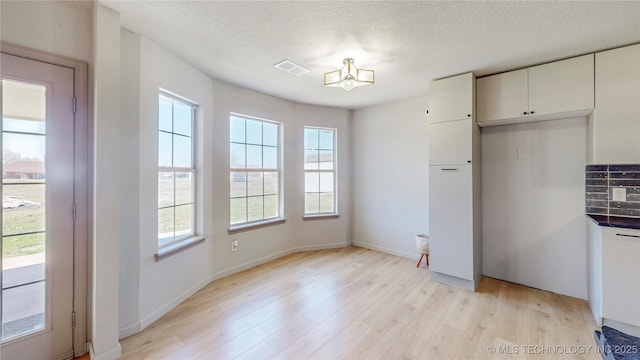 11762 N 156th E Ave, Collinsville, OK 74021 - unfurnished dining area with light wood-type flooring, a chandelier, a textured ceiling, and baseboards