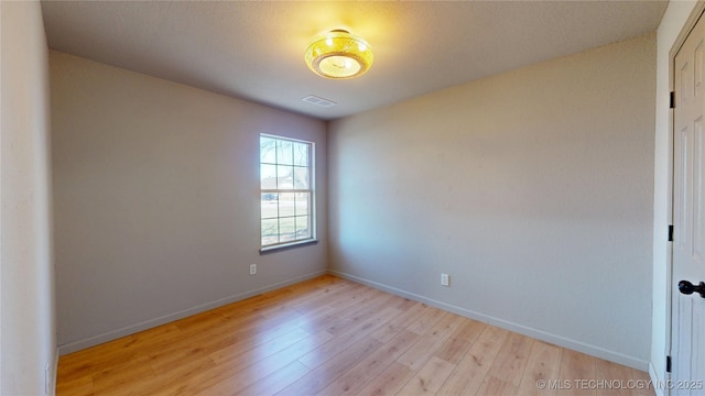 spare room featuring baseboards, light wood-style flooring, and visible vents