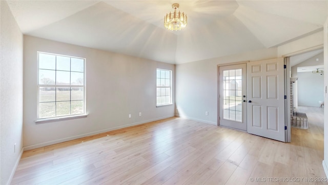 foyer featuring an inviting chandelier, baseboards, vaulted ceiling, and light wood-style floors