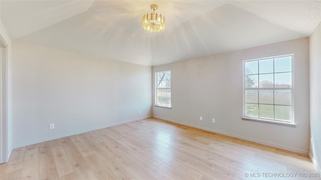 unfurnished room featuring baseboards, light wood-style floors, and a chandelier