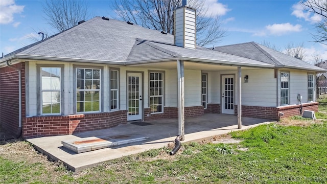 rear view of house featuring french doors, a chimney, brick siding, and a patio area