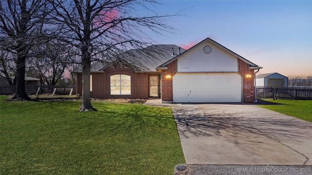 ranch-style house featuring a front yard, concrete driveway, an attached garage, fence, and brick siding