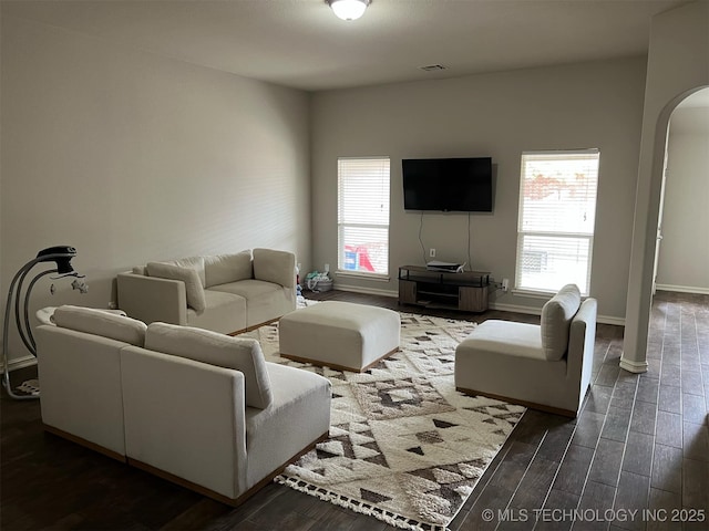 living room featuring plenty of natural light, baseboards, wood finished floors, and arched walkways