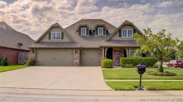 craftsman inspired home featuring a shingled roof, driveway, brick siding, a front yard, and a garage
