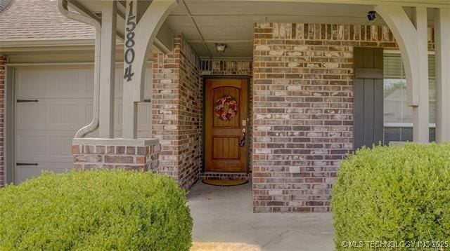 entrance to property featuring brick siding and roof with shingles