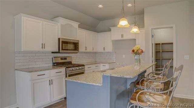 kitchen with white cabinets, stainless steel appliances, light stone countertops, and tasteful backsplash