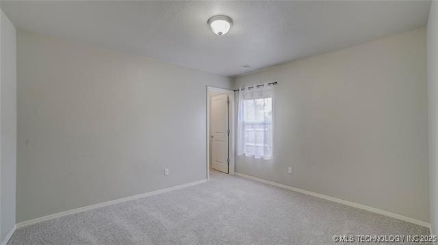 carpeted spare room featuring baseboards