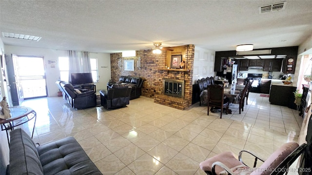 living room featuring visible vents, a fireplace, a textured ceiling, and ceiling fan
