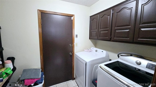 clothes washing area featuring separate washer and dryer, light tile patterned flooring, cabinet space, and a textured ceiling