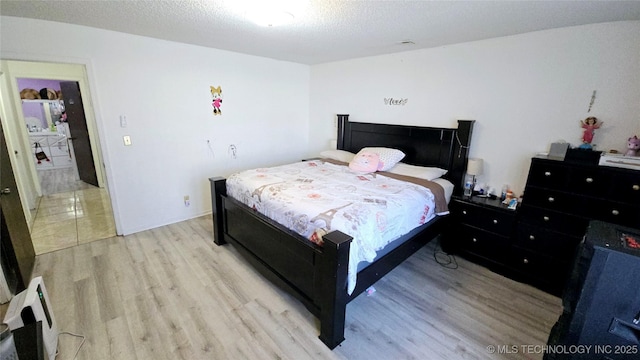 bedroom featuring light wood finished floors and a textured ceiling