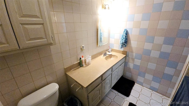 bathroom featuring vanity, tile walls, and toilet