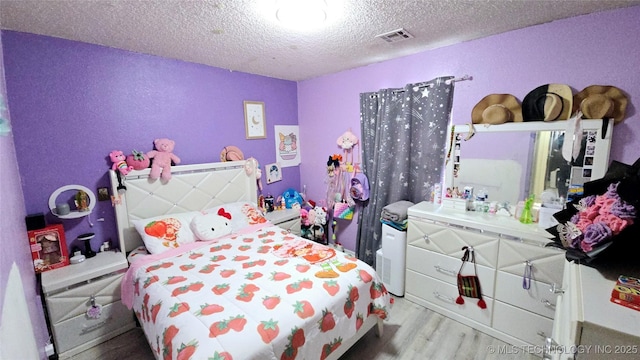 bedroom featuring visible vents, a textured ceiling, and wood finished floors
