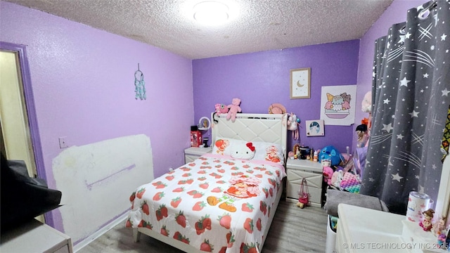 bedroom with a textured ceiling and wood finished floors