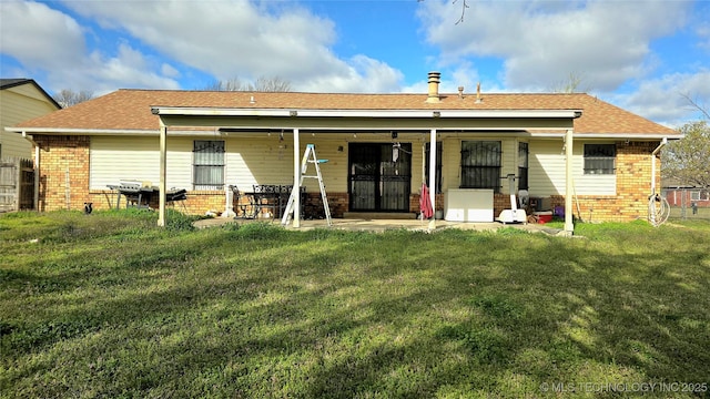 rear view of property with brick siding and a lawn