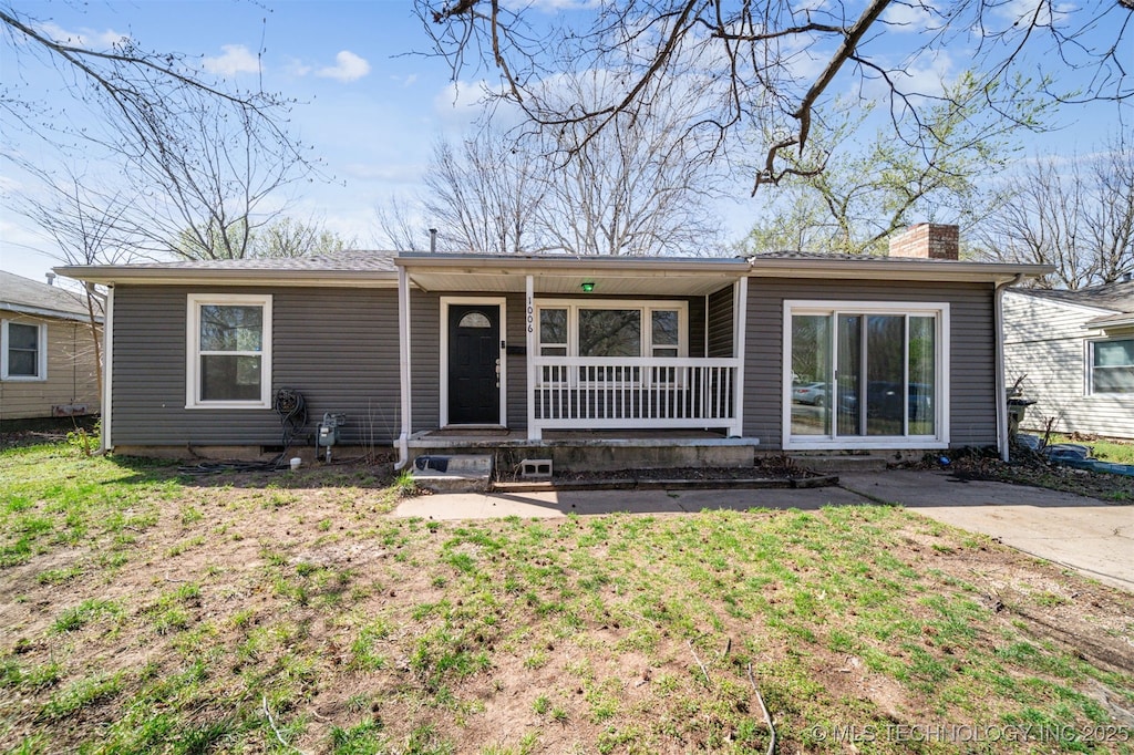view of front of property with a front lawn, covered porch, and a chimney