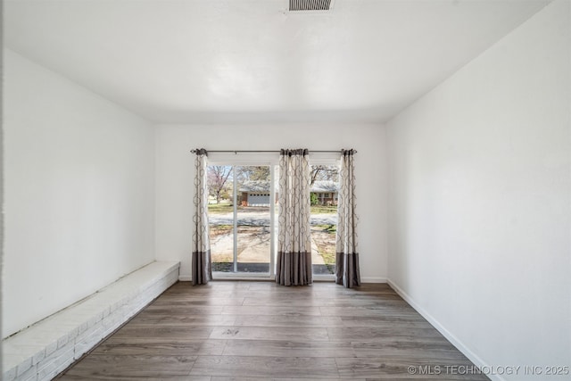 unfurnished room with visible vents, baseboards, and wood finished floors