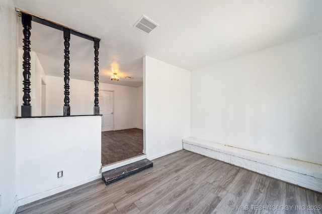spare room featuring wood finished floors, visible vents, and baseboards