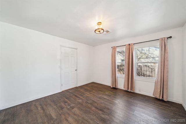 unfurnished room featuring visible vents, baseboards, and dark wood-type flooring