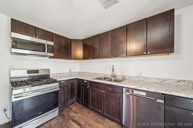 kitchen with visible vents, dark wood-type flooring, a sink, dark brown cabinetry, and appliances with stainless steel finishes