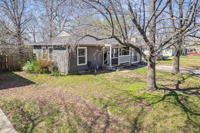 view of front of house featuring covered porch, a front yard, and fence