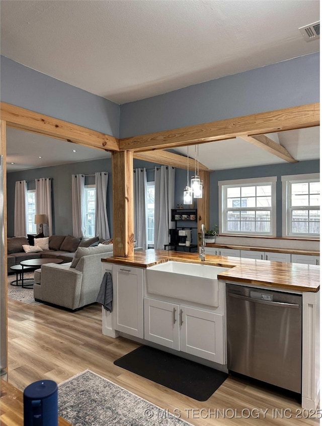 kitchen with visible vents, a sink, stainless steel dishwasher, white cabinetry, and butcher block counters