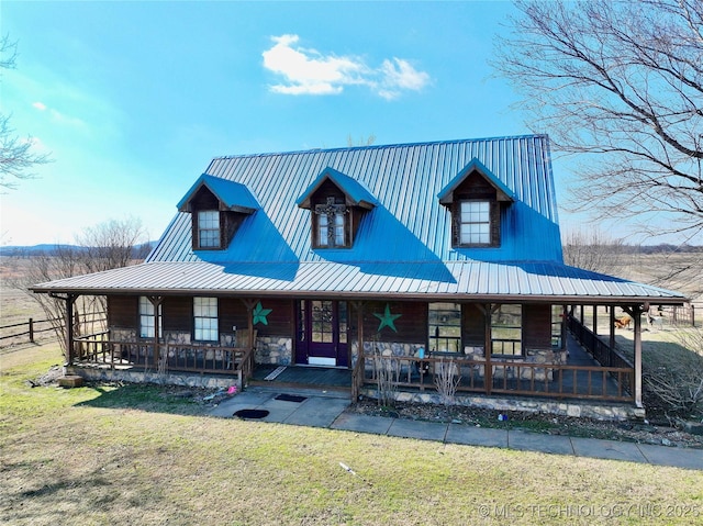 farmhouse inspired home featuring metal roof, stone siding, covered porch, and a front lawn