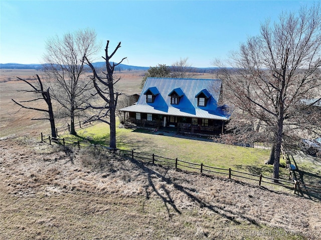 view of front of home featuring metal roof, covered porch, a front yard, and fence
