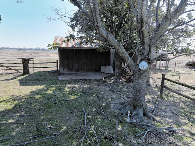 view of outbuilding featuring an outbuilding, a rural view, and fence