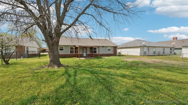 313 S Fairfax Ave, Skiatook, OK 74070 - rear view of property featuring a fenced backyard, brick siding, and a lawn