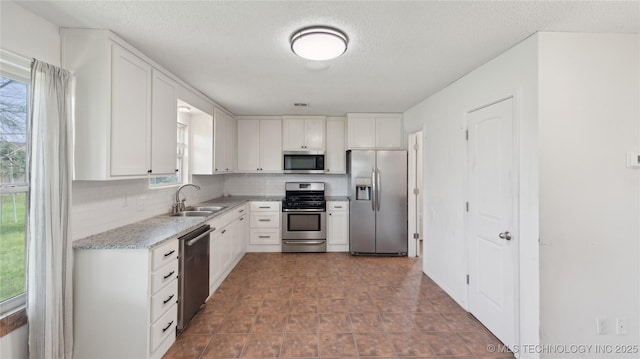 313 S Fairfax Ave, Skiatook, OK 74070 - kitchen featuring stainless steel appliances, a textured ceiling, backsplash, a sink, and white cabinets