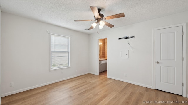 313 S Fairfax Ave, Skiatook, OK 74070 - unfurnished bedroom featuring a textured ceiling, light wood-type flooring, ensuite bathroom, baseboards, and visible vents