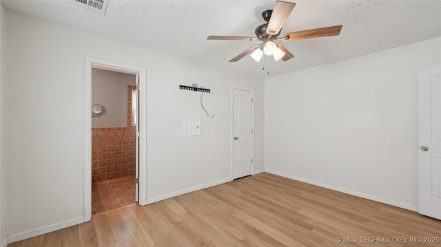 313 S Fairfax Ave, Skiatook, OK 74070 - unfurnished bedroom with ensuite bath, a textured ceiling, visible vents, and light wood-style floors