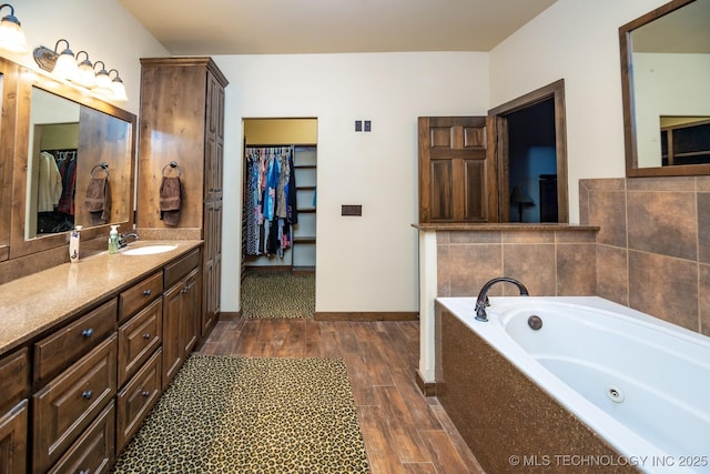 358653 E 5700th Rd, Jennings, OK 74038 - bathroom featuring wood finished floors, a walk in closet, vanity, a whirlpool tub, and baseboards