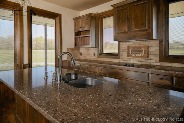 kitchen with dark stone counters, decorative backsplash, and a sink