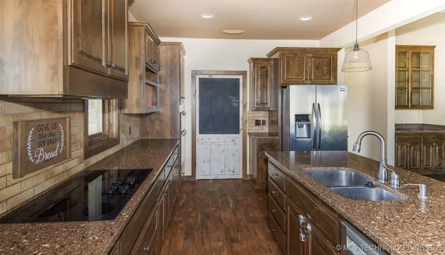 kitchen featuring stainless steel appliances, a sink, dark stone countertops, pendant lighting, and dark wood-type flooring