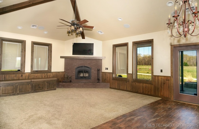 unfurnished living room featuring wainscoting, plenty of natural light, vaulted ceiling with beams, and ceiling fan with notable chandelier