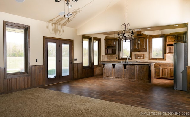 kitchen with freestanding refrigerator, plenty of natural light, a wainscoted wall, and a notable chandelier