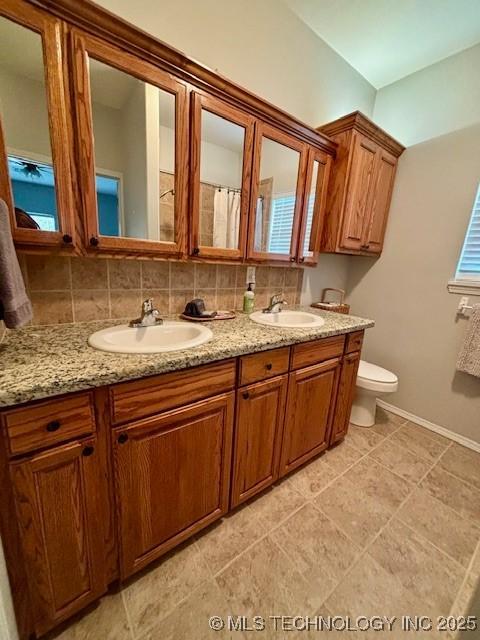 142 Elm St, Mannford, OK 74044 - bathroom featuring toilet, double vanity, and baseboards