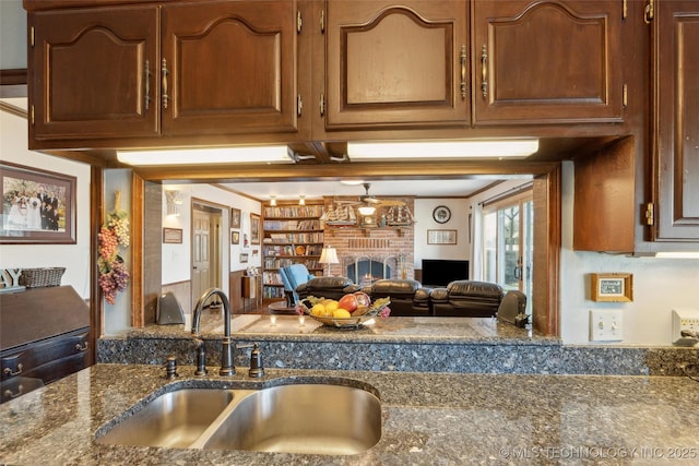 108 S Bettes Ave, Wagoner, OK 74467 - kitchen featuring crown molding, dark stone countertops, a sink, and a brick fireplace
