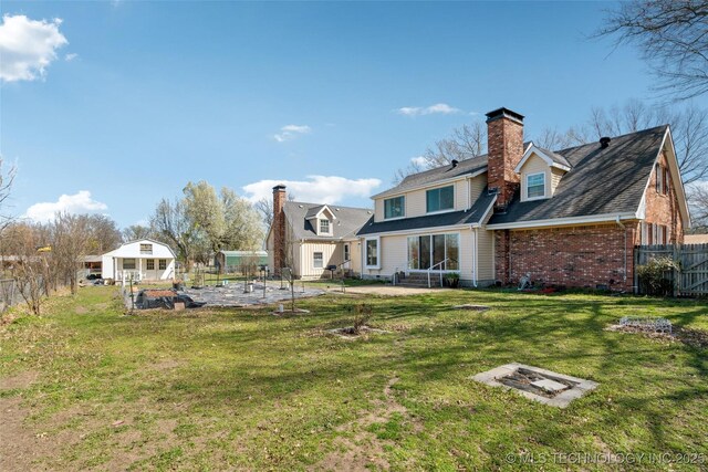 108 S Bettes Ave, Wagoner, OK 74467 - rear view of house featuring a chimney, fence, brick siding, and a yard