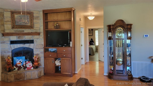 6111 County Road 3605, Ada, OK 74820 - living area with light wood-type flooring, a textured ceiling, visible vents, a ceiling fan, and a fireplace