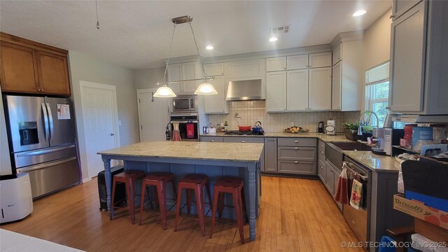 6111 County Road 3605, Ada, OK 74820 - kitchen featuring a breakfast bar, decorative backsplash, visible vents, wall chimney range hood, and appliances with stainless steel finishes