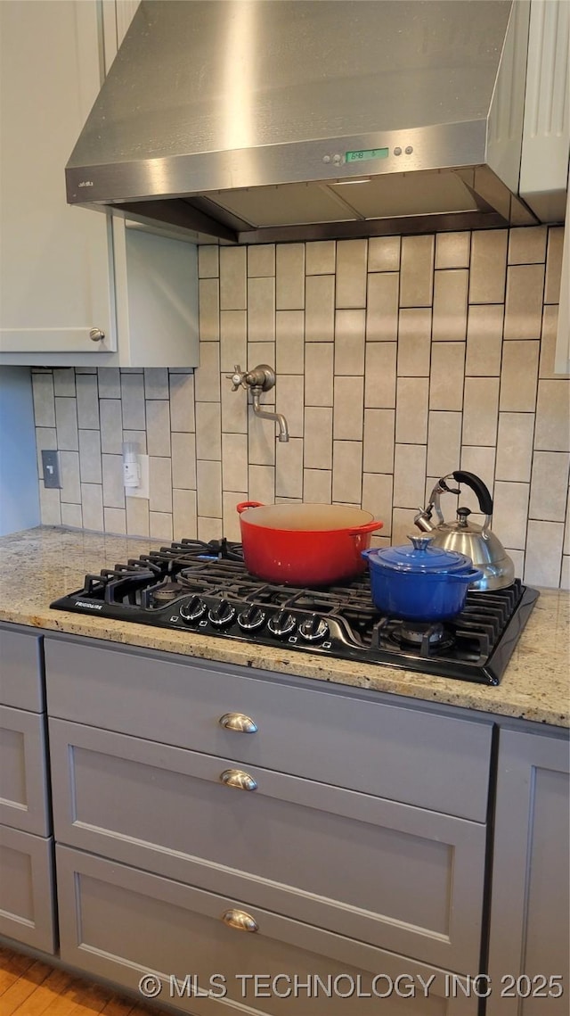 6111 County Road 3605, Ada, OK 74820 - kitchen with gray cabinets, black gas stovetop, light stone countertops, under cabinet range hood, and decorative backsplash