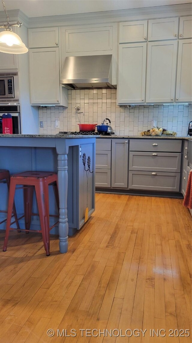 6111 County Road 3605, Ada, OK 74820 - kitchen with stainless steel appliances, wall chimney exhaust hood, gray cabinets, and tasteful backsplash