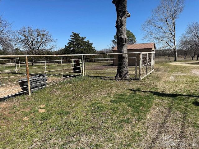 view of yard featuring an outbuilding, fence, and a rural view