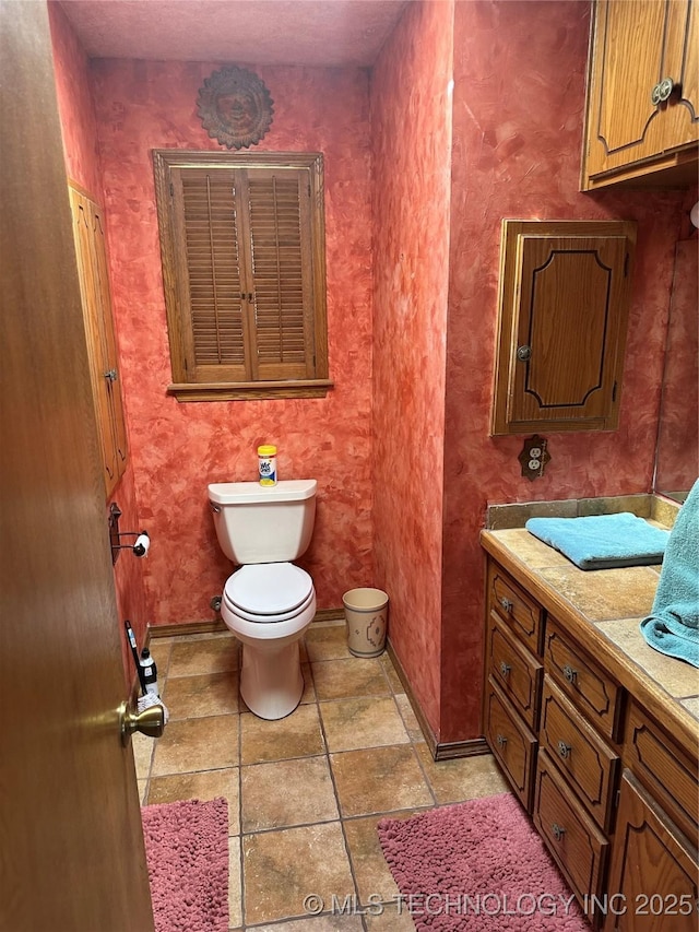 bathroom with toilet, vanity, and baseboards