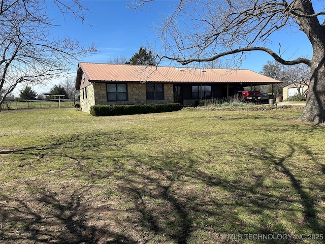 single story home with fence, metal roof, a front yard, and stone siding