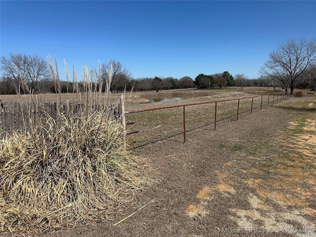 view of yard featuring a water view, fence, and a rural view