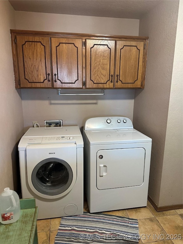laundry area with baseboards, cabinet space, and washer and clothes dryer
